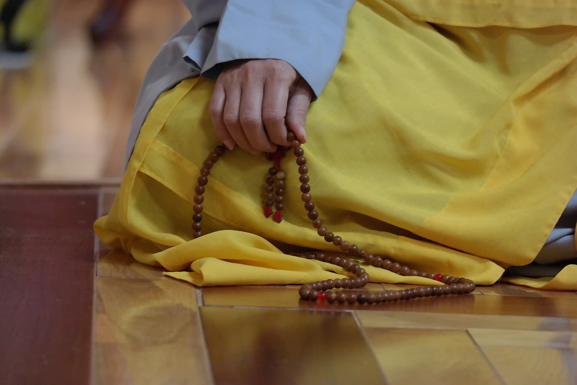 A Buddhist nun's hand holding mala beads used for mantra recitation