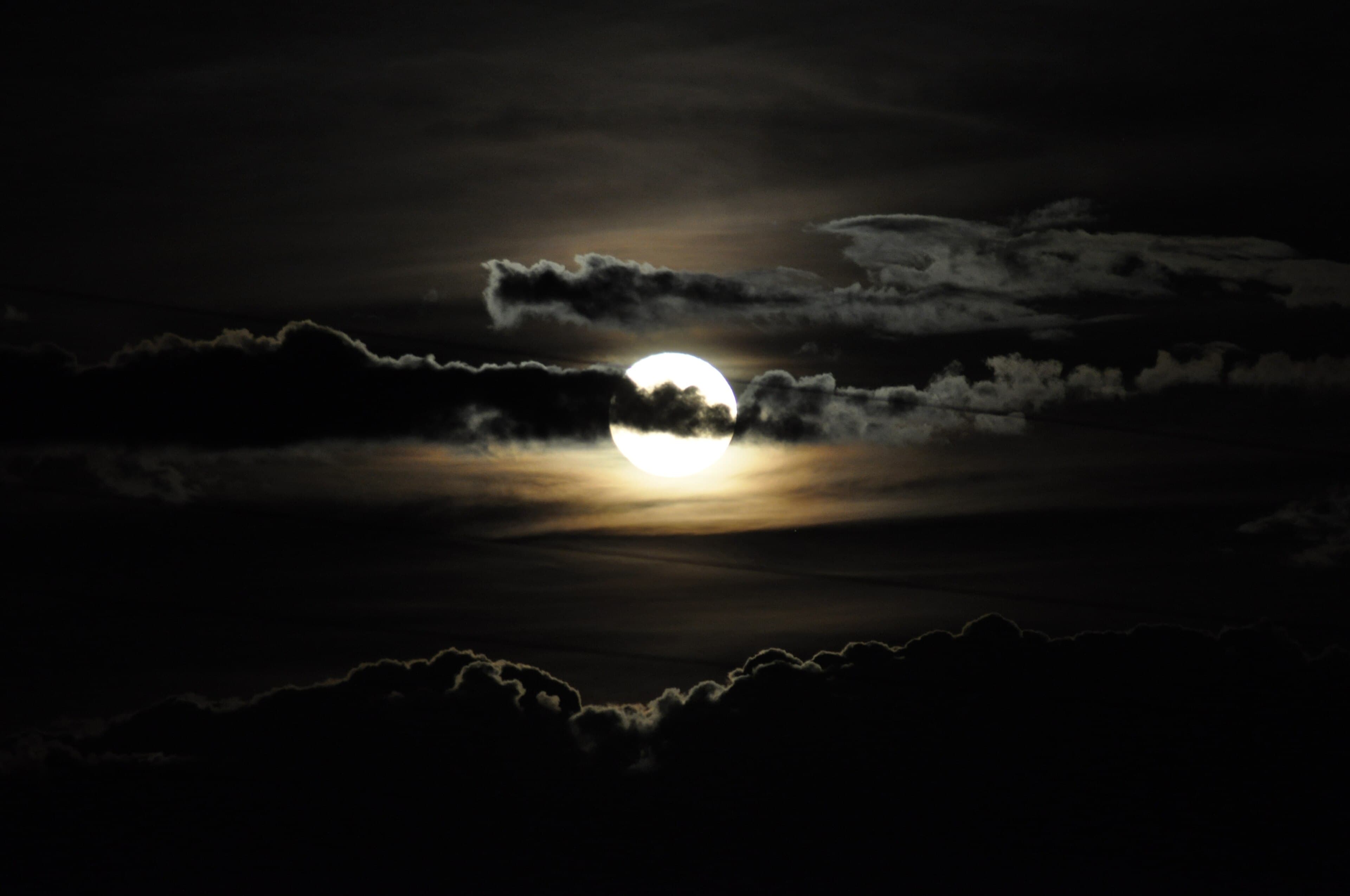The full moon emerging from behind dark clouds, illustrating the essay's own image of buddha-nature briefly obscured but never diminished