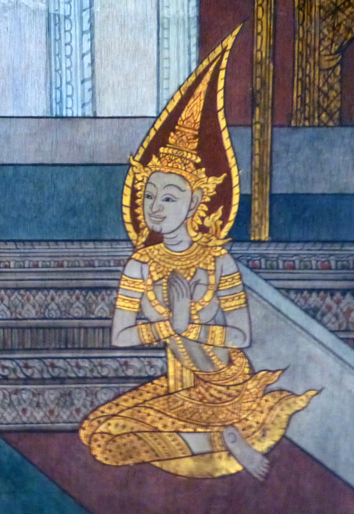 Thai mural painting of Yashodhara seated in devotional posture, hands folded, wearing a flame-topped royal headdress