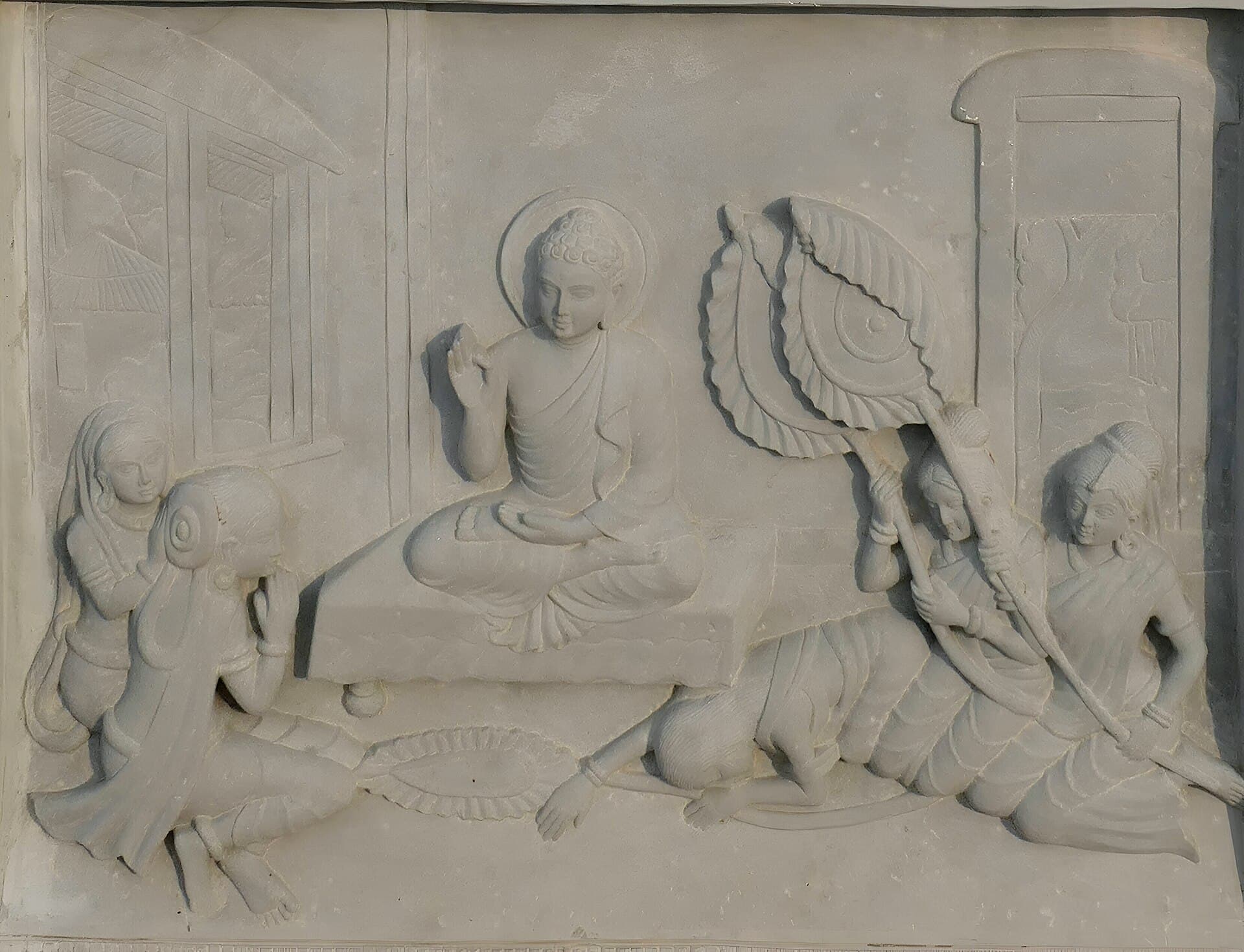 Stone relief carving titled "Queen Khema Sees a Woman Age and Die," depicting the seated Buddha teaching Khema with attendants and a canopy nearby