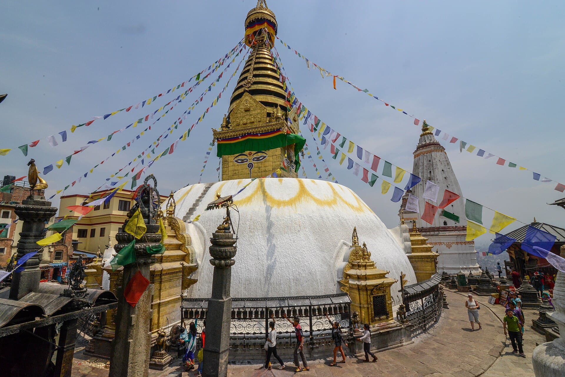 Pilgrims circumambulating the Swayambhunath stupa clockwise while spinning prayer wheels